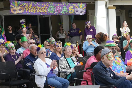 Chateau Madeleine residents seated and dressed for Mardi Gras acrobatic show