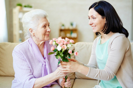 Woman handing a senior woman flowers for Mothers Day