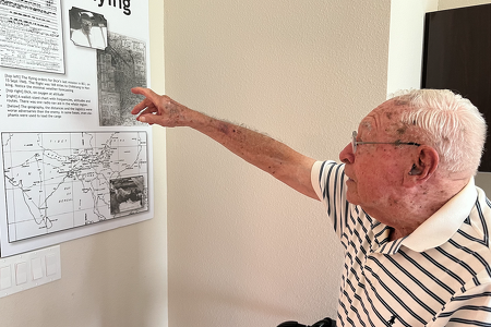 Chateau Madeleine senior man points to image from WWII