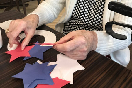 Resident Making Crafts with Red, White, and Blue Construction Paper Stars