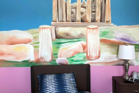 Bed and end table in front of mural of ancient Rome 