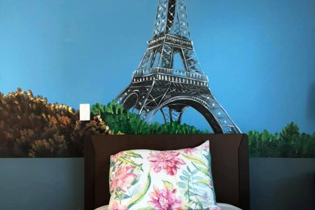 Bed in front of a mural of the Eiffel Tower