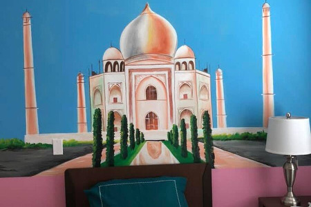 Bed and end table in front of mural of the Taj Mahal