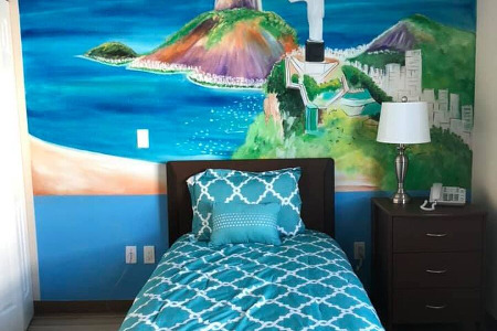 Bed and end table in front of mural