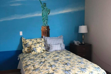 Bed and end table in front of mural of the Statue of Liberty 