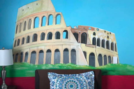 Bed and end table in front of mural of Colosseum