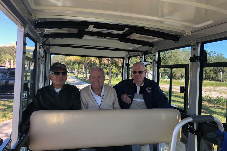 Three older men sitting in a tram